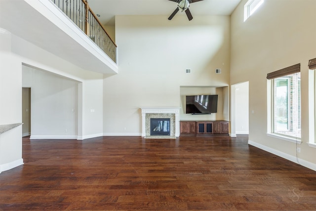 unfurnished living room featuring dark wood-type flooring, a fireplace, visible vents, a ceiling fan, and baseboards