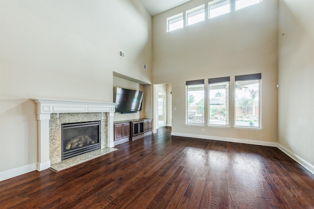 unfurnished living room with dark wood-style floors, visible vents, baseboards, and a premium fireplace