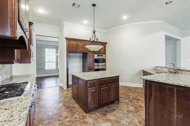 kitchen with hanging light fixtures, light stone countertops, visible vents, and a sink