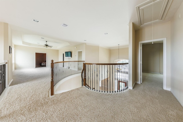 corridor with light carpet, attic access, visible vents, a raised ceiling, and baseboards