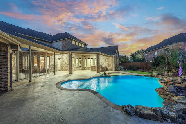 pool at dusk featuring fence, a fenced in pool, and a patio