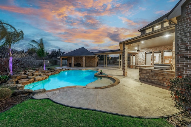 view of pool featuring an outdoor kitchen, a fenced in pool, a patio, ceiling fan, and fence