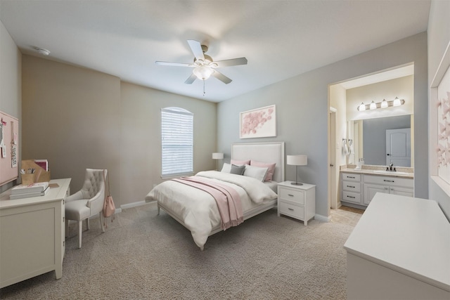 bedroom featuring light colored carpet, ensuite bath, and baseboards