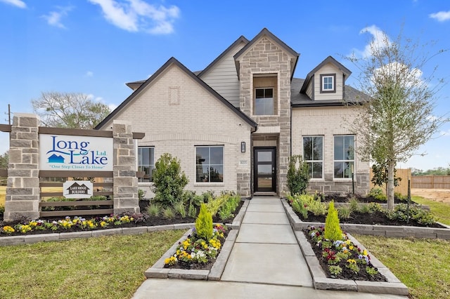 view of front facade featuring stone siding, brick siding, and a front lawn