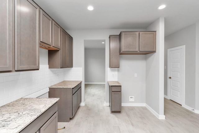 kitchen featuring baseboards, light wood finished floors, backsplash, and recessed lighting