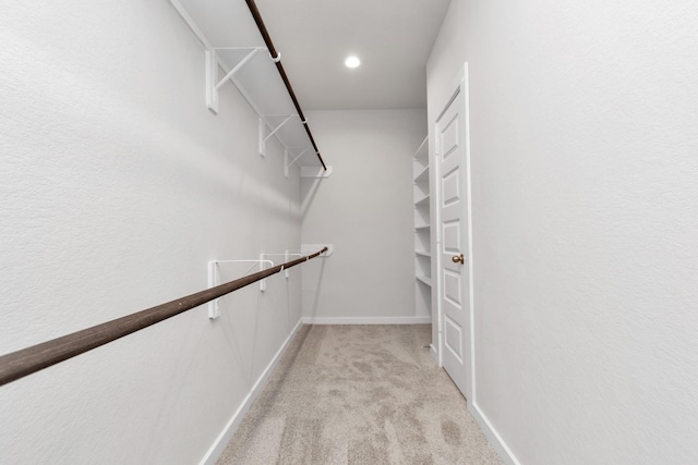 walk in closet with light colored carpet