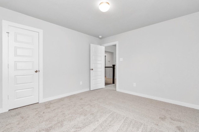 spare room with light carpet and baseboards