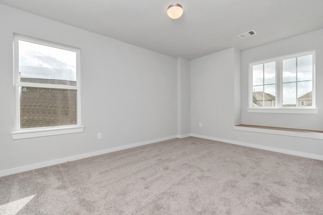 spare room featuring light carpet, visible vents, and baseboards