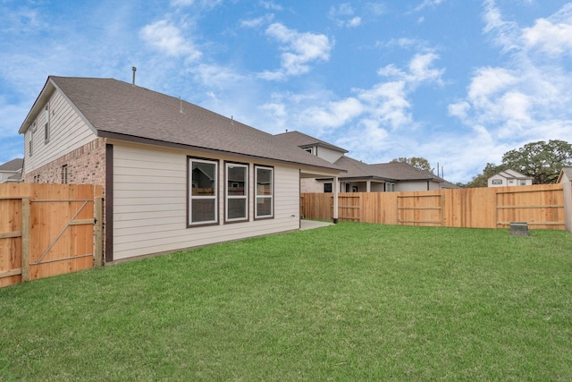 rear view of property with a gate, a fenced backyard, a yard, and brick siding