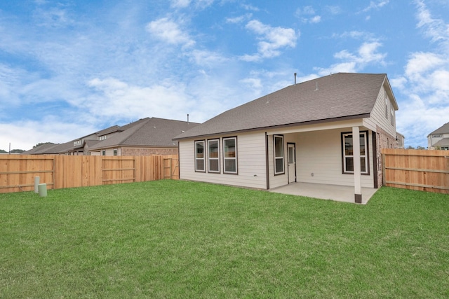 back of property with a shingled roof, a lawn, a patio area, and a fenced backyard