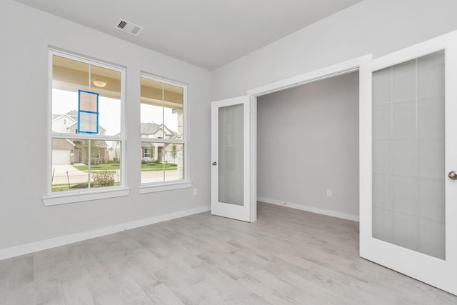 empty room featuring french doors, visible vents, and baseboards