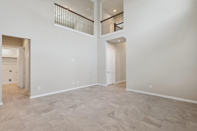 spare room featuring visible vents, recessed lighting, a towering ceiling, and baseboards