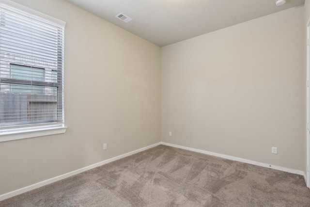 spare room featuring baseboards, visible vents, and carpet flooring