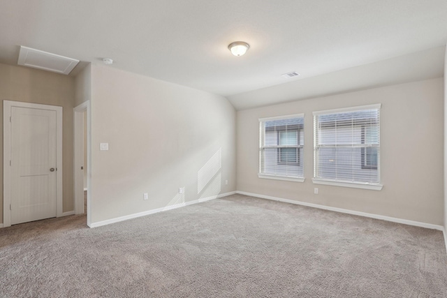 unfurnished room featuring lofted ceiling, visible vents, baseboards, carpet, and attic access