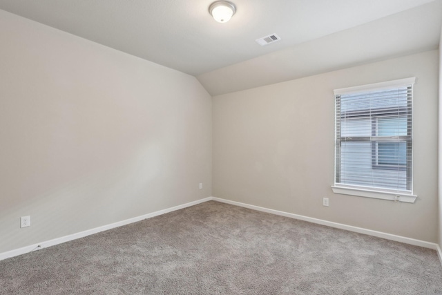 empty room with light carpet, vaulted ceiling, visible vents, and baseboards