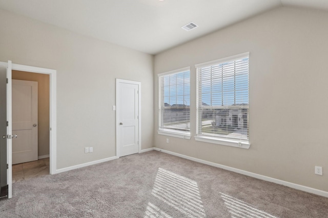 unfurnished bedroom with light carpet, vaulted ceiling, visible vents, and baseboards