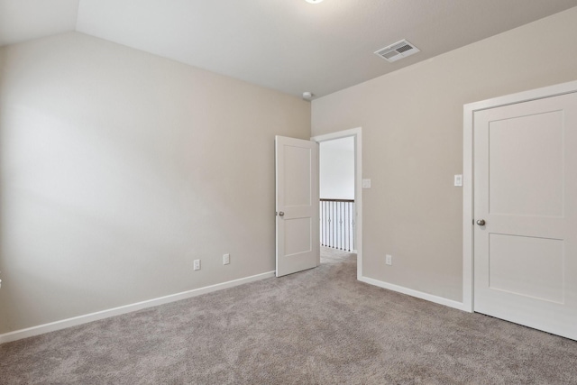 unfurnished bedroom featuring light carpet, lofted ceiling, visible vents, and baseboards