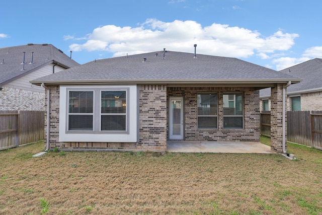 rear view of property with a lawn, a fenced backyard, roof with shingles, a patio area, and brick siding