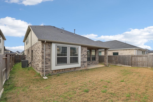 back of property with brick siding, a lawn, central AC unit, and a fenced backyard