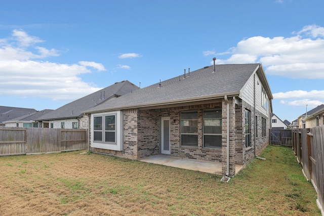 rear view of house featuring a shingled roof, a patio, a fenced backyard, a yard, and brick siding