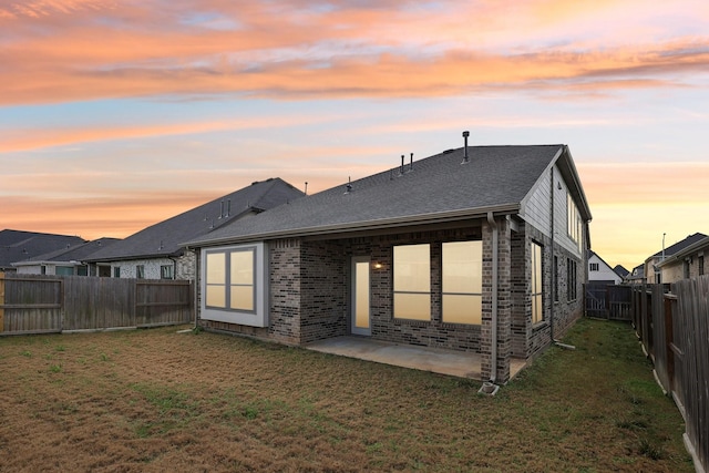 back of house with a patio, a fenced backyard, brick siding, a shingled roof, and a yard