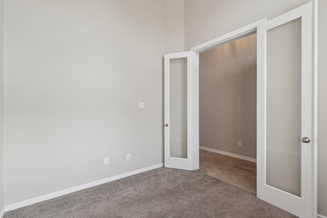 unfurnished bedroom featuring french doors, light carpet, and baseboards