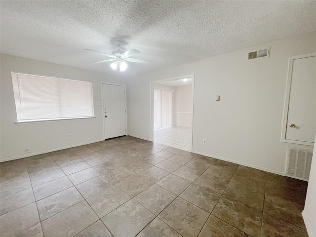 unfurnished room with visible vents, ceiling fan, a textured ceiling, and light tile patterned floors