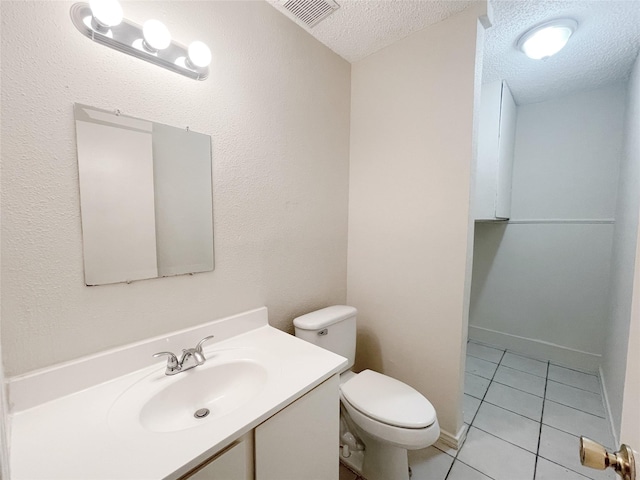 half bathroom featuring visible vents, toilet, a textured ceiling, vanity, and tile patterned flooring