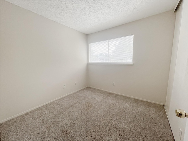 empty room with carpet floors, baseboards, and a textured ceiling