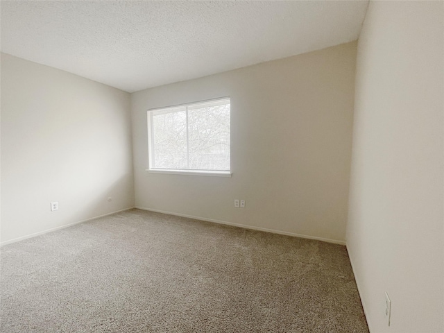 carpeted empty room featuring a textured ceiling and baseboards