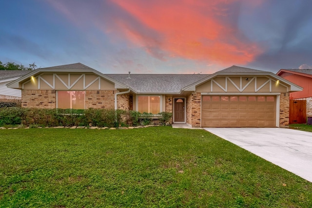 tudor home featuring an attached garage, driveway, a front lawn, and brick siding