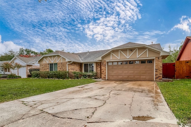 view of front of house with an attached garage, brick siding, fence, concrete driveway, and a front yard