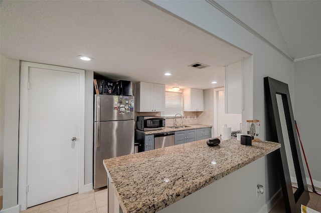 kitchen featuring stainless steel appliances, a peninsula, a sink, visible vents, and white cabinetry