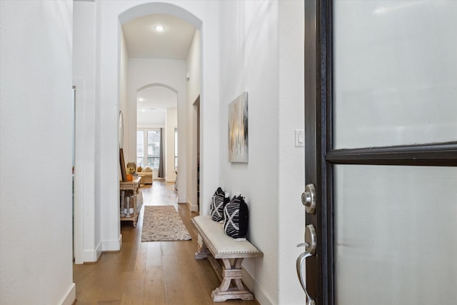 interior space with arched walkways, baseboards, and wood finished floors