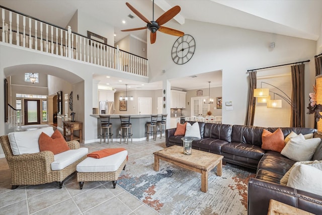 living room featuring light tile patterned flooring, ceiling fan with notable chandelier, visible vents, baseboards, and vaulted ceiling