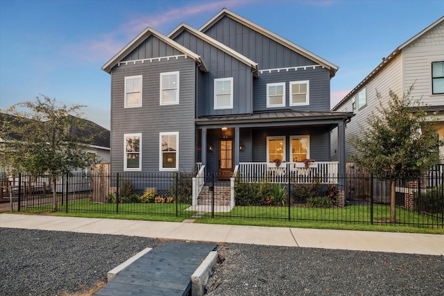 view of front of property with a lawn, a fenced front yard, covered porch, a standing seam roof, and board and batten siding