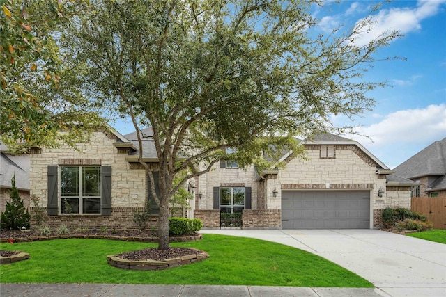 view of front of home featuring fence, stone siding, a front lawn, an attached garage, and driveway