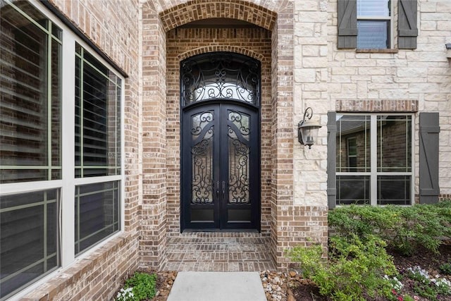 entrance to property with brick siding, french doors, and stone siding