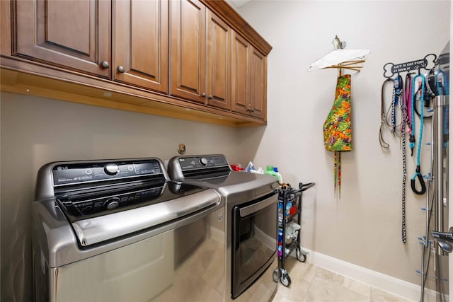 washroom with cabinet space, baseboards, and separate washer and dryer