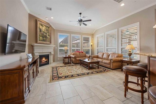 living room featuring crown molding, visible vents, ceiling fan, and a lit fireplace