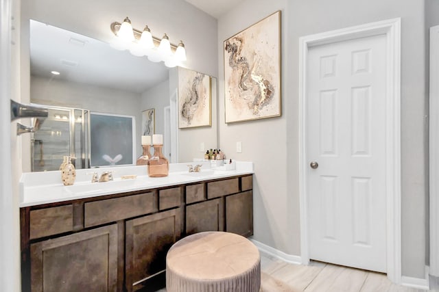 bathroom featuring a sink, a shower stall, baseboards, and double vanity