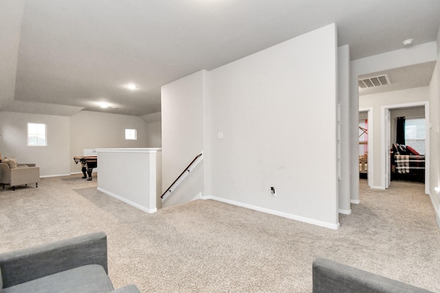 living area featuring visible vents, light carpet, and baseboards