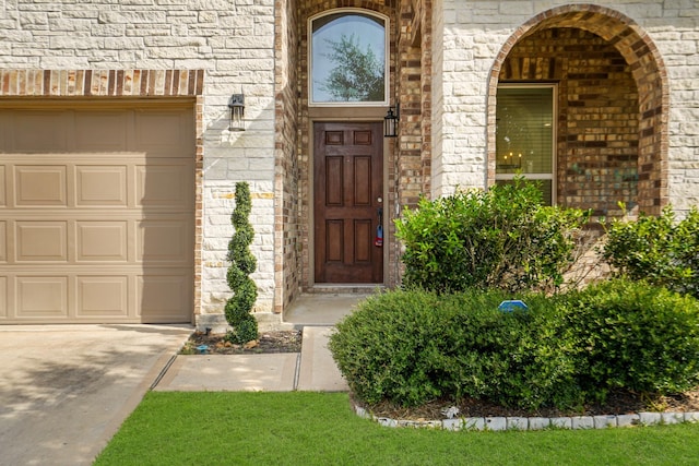 property entrance with a garage, stone siding, and brick siding