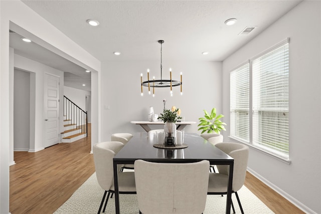 dining area featuring visible vents, baseboards, stairs, light wood-style floors, and an inviting chandelier