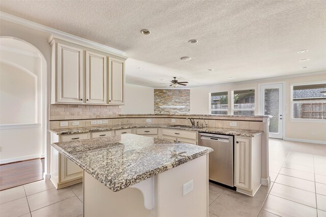 13006 Freemont Peak Ln, Humble, TX 77346 - kitchen with cream cabinets, stainless steel dishwasher, a peninsula, a sink, and a textured ceiling