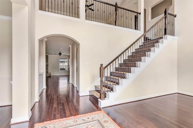 13006 Freemont Peak Ln, Humble, TX 77346 - stairs featuring arched walkways, ceiling fan, wood finished floors, a high ceiling, and baseboards