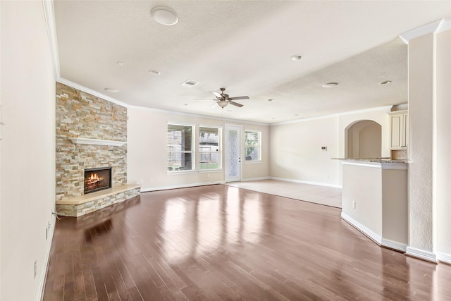 13006 Freemont Peak Ln, Humble, TX 77346 - unfurnished living room with crown molding, ceiling fan, wood finished floors, baseboards, and a stone fireplace