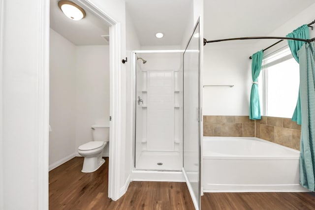 full bath featuring a garden tub, a shower stall, toilet, and wood finished floors