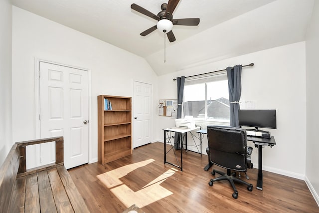 home office featuring a ceiling fan, baseboards, vaulted ceiling, and wood finished floors