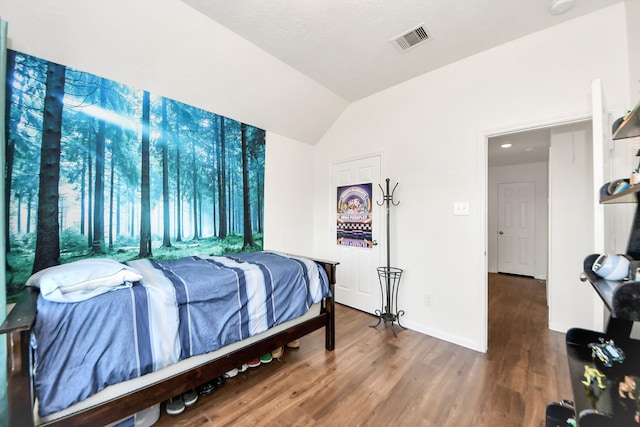 bedroom with lofted ceiling, wood finished floors, visible vents, and baseboards